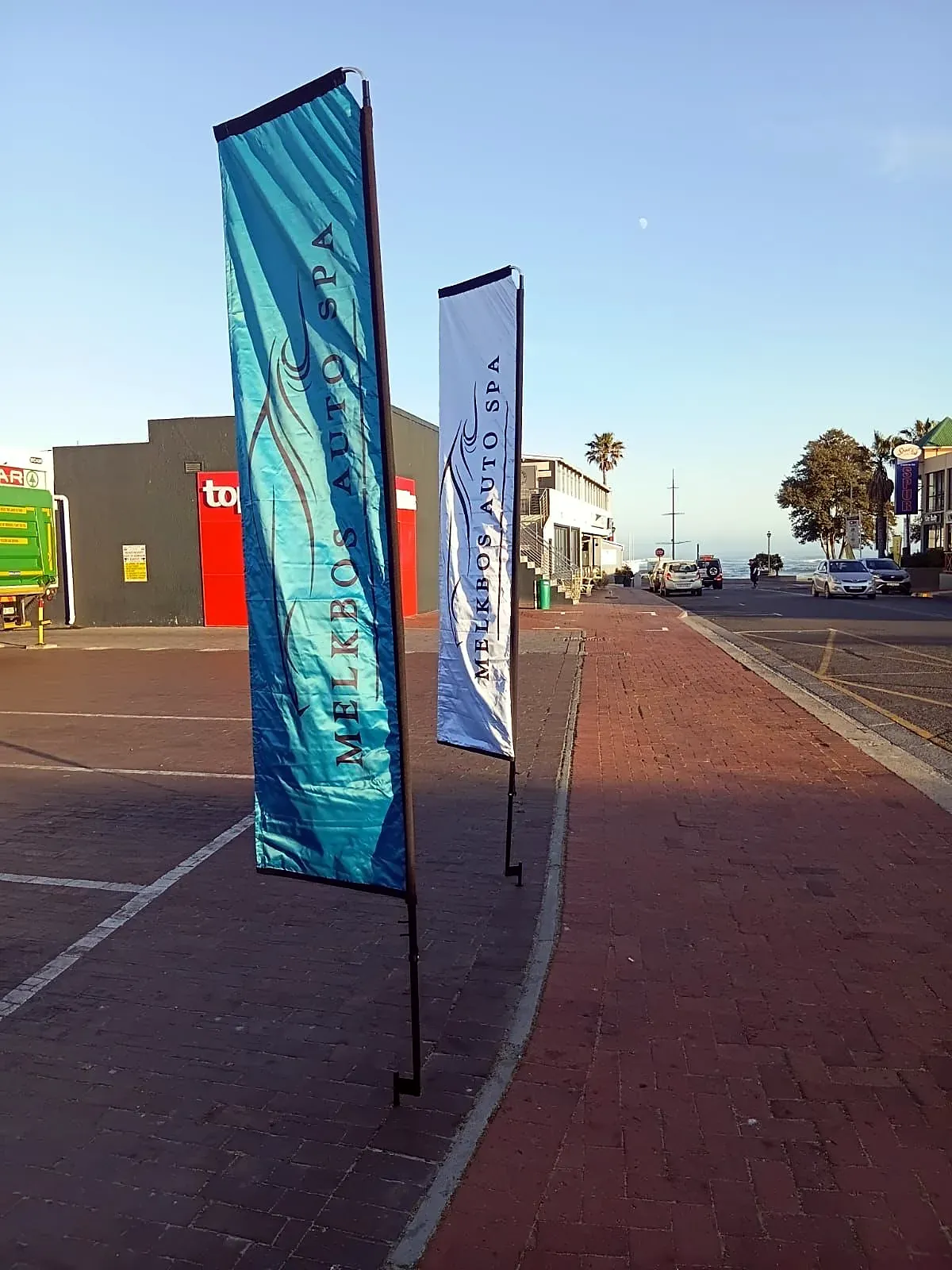 Two Melkbos Auto Spa flags on the pavement outside the branch in Melkbosstrand