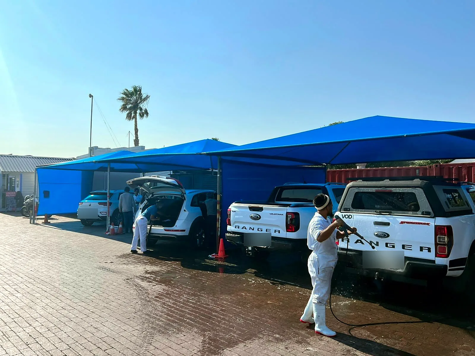 A Melkbos Auto Spa detailer washing a bakkie under the blue shade ports